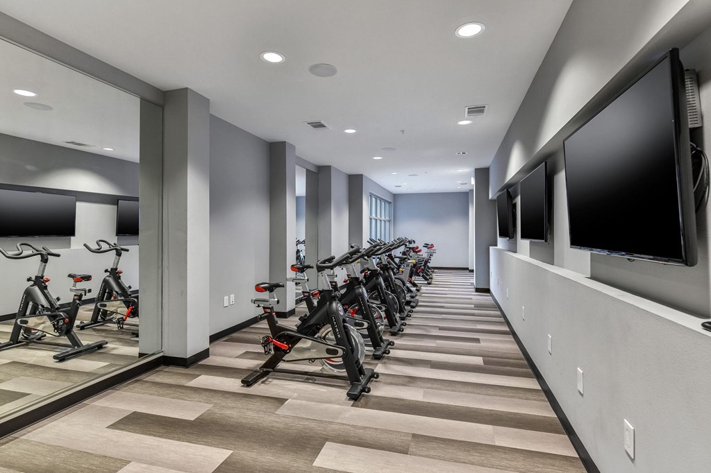 A row of exercise bikes are lined up in a room.