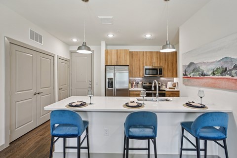 A kitchen with a white counter and blue chairs.