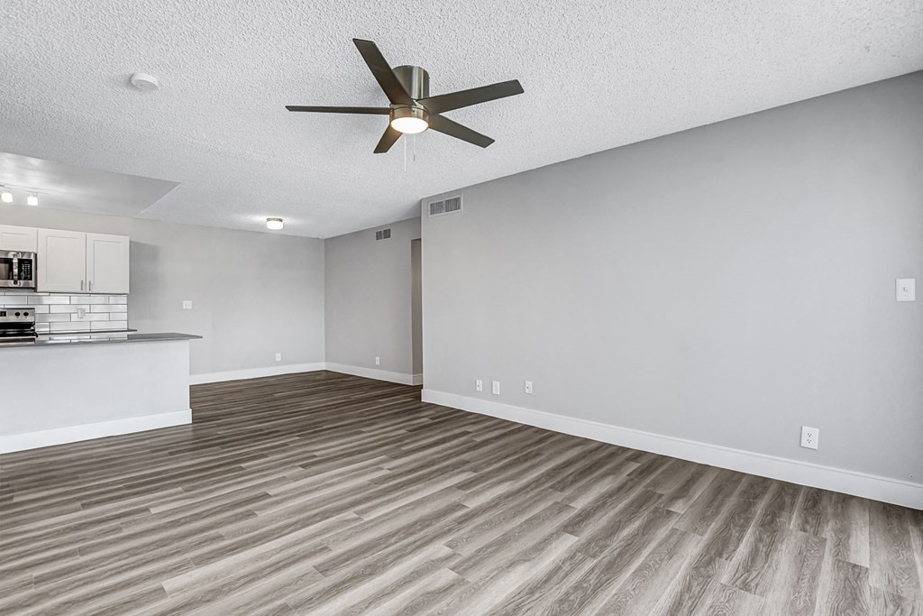 an empty living room with a ceiling fan