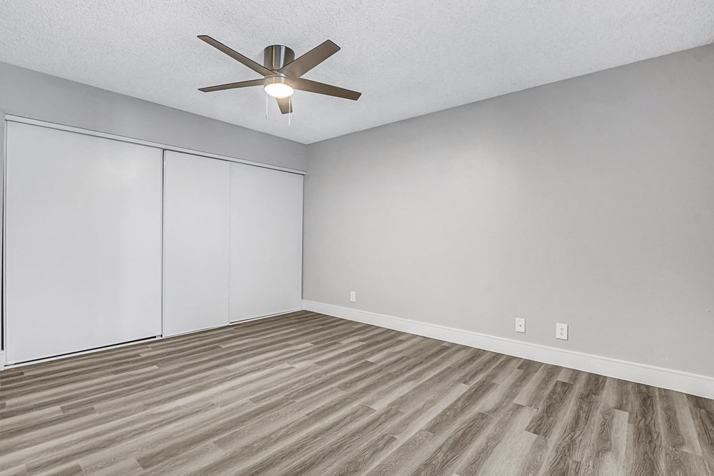 a bedroom with grey walls and a ceiling fan