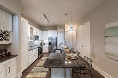 a kitchen with white cabinets and a black table