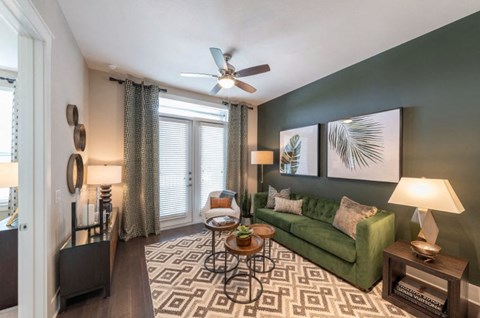 a living room with a green couch and a ceiling fan