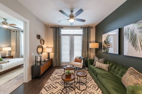 a living room with a green couch and a ceiling fan
