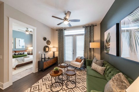 a living room with a green couch and a ceiling fan