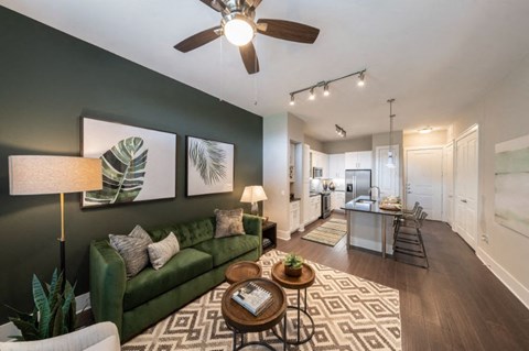a living room with a green couch and a ceiling fan