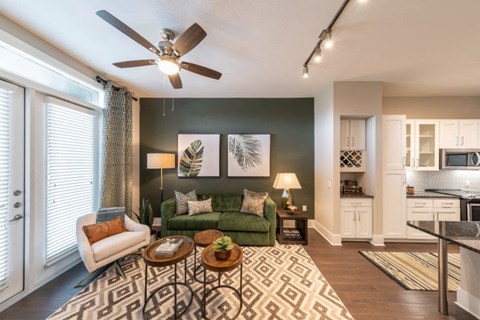 a living room with a green couch and a ceiling fan