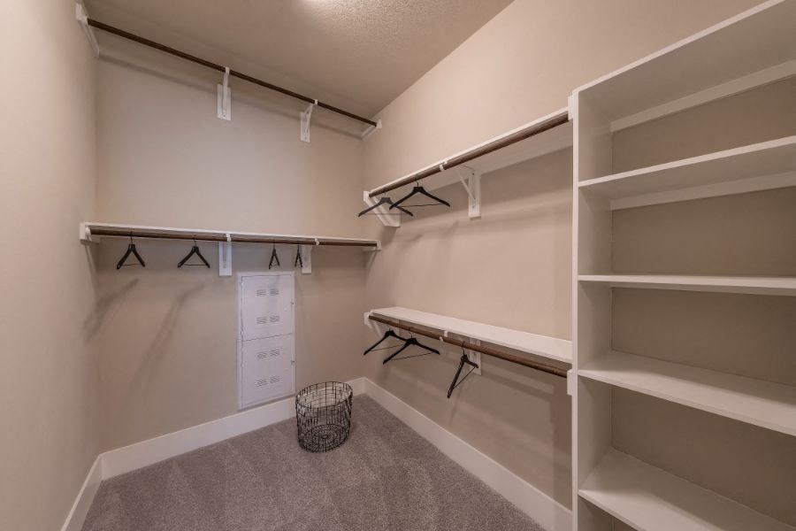 a large walk in closet with shelves and a bench