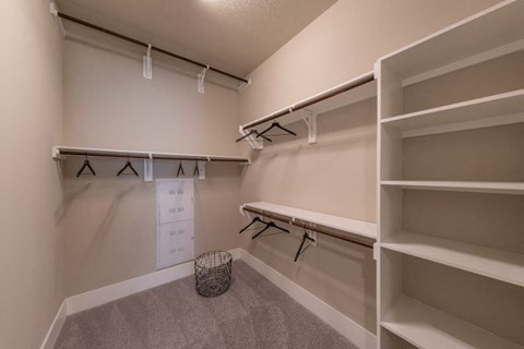 a large walk in closet with shelves and a bench
