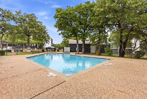 A pool surrounded by trees and a fence.