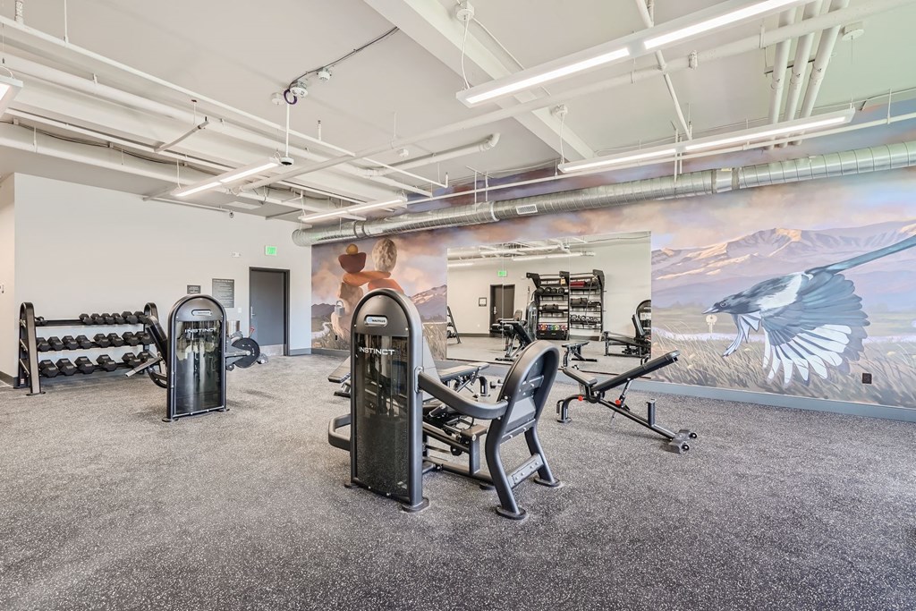 a workout room with exercise machines and a mural of a bird