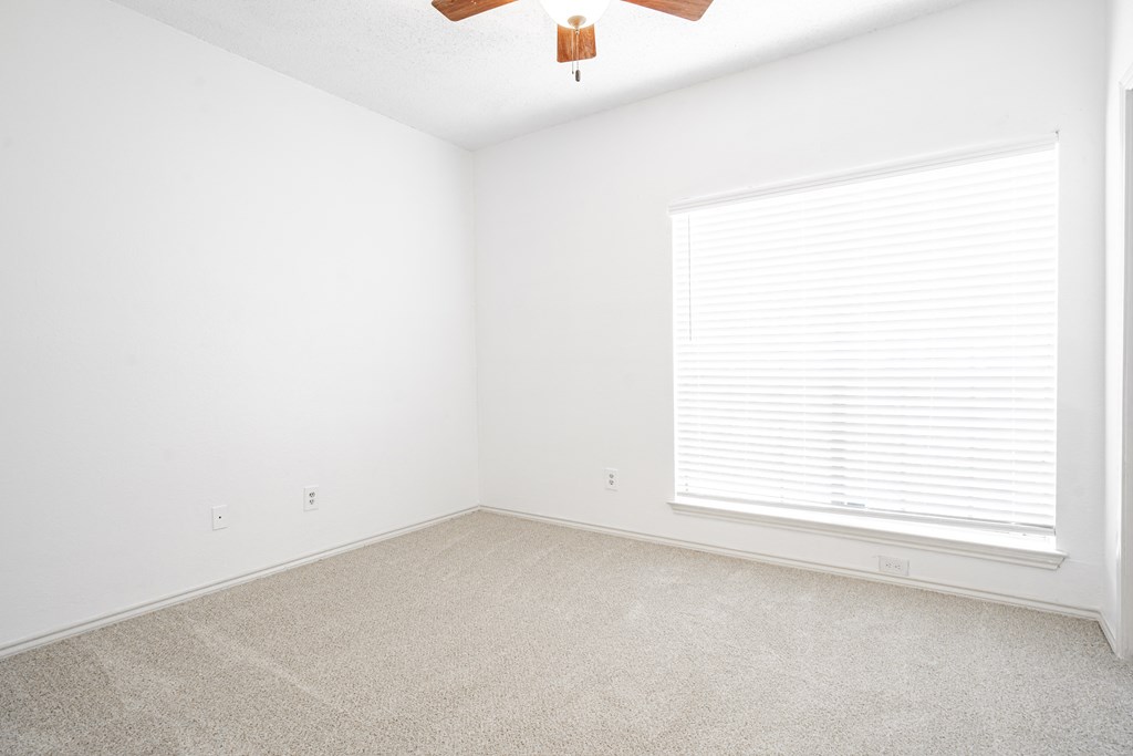 an empty room with a window and a ceiling fan
