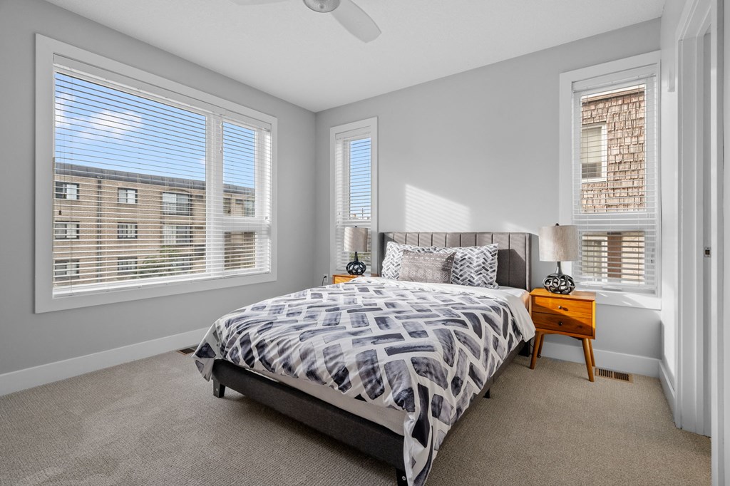 a bedroom with a bed and two windows