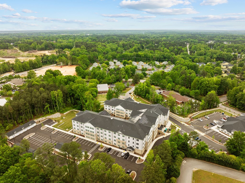 an aerial view of a building surrounded by trees and a parking lot