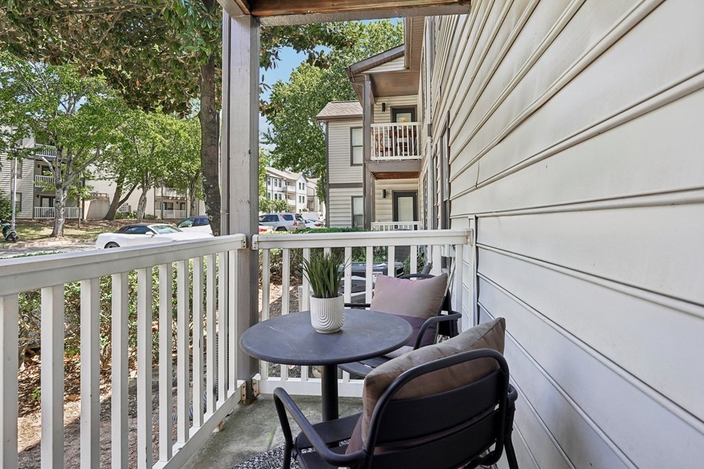A patio with a table and chairs overlooking a parking lot.