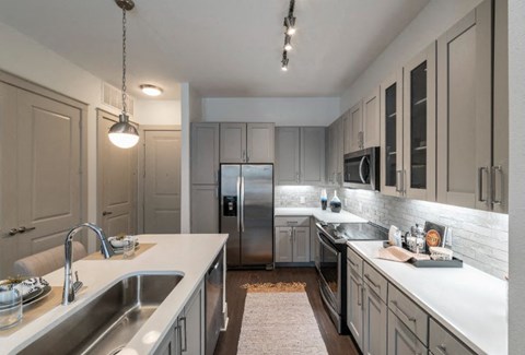 a large kitchen with stainless steel appliances and white counters