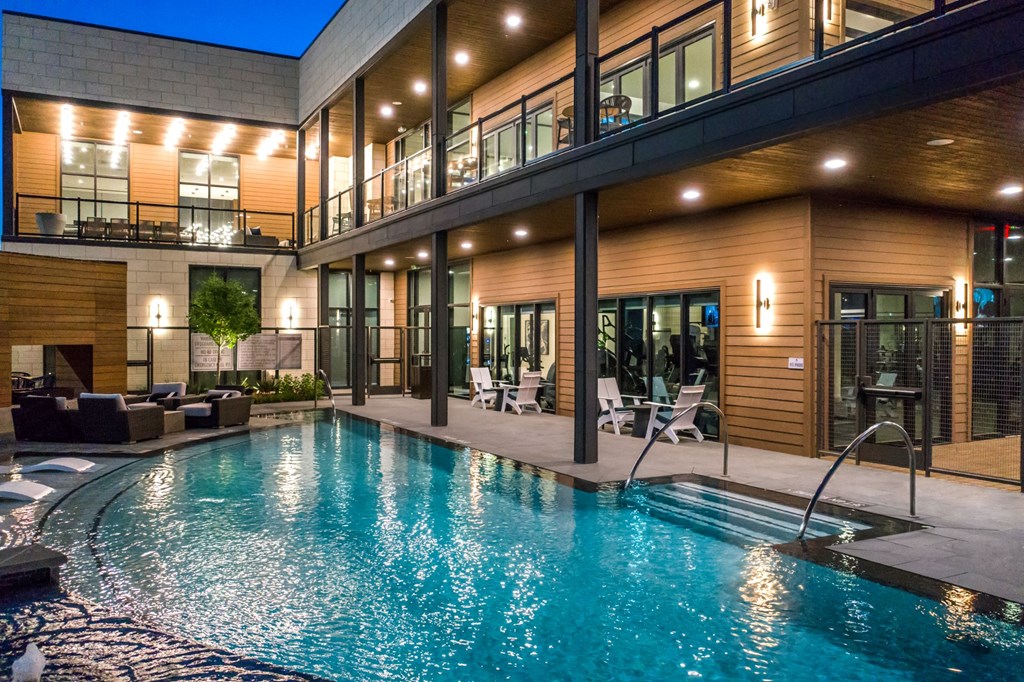 a swimming pool in front of a house with a large glass door