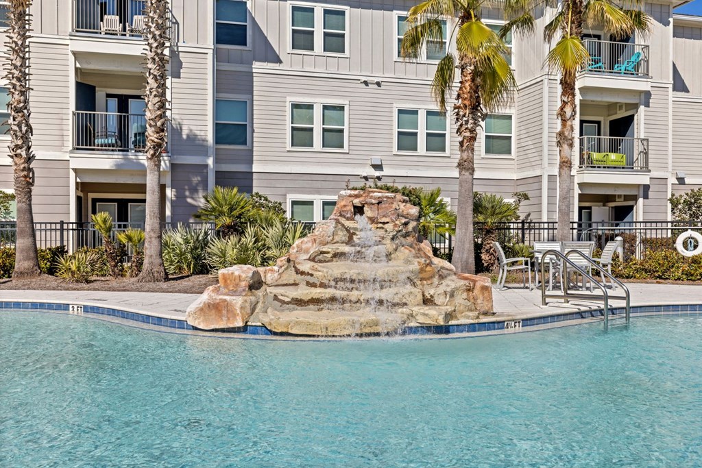 A pool with a rock fountain in the middle of it.