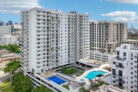 A large white residential building with a pool in the middle.