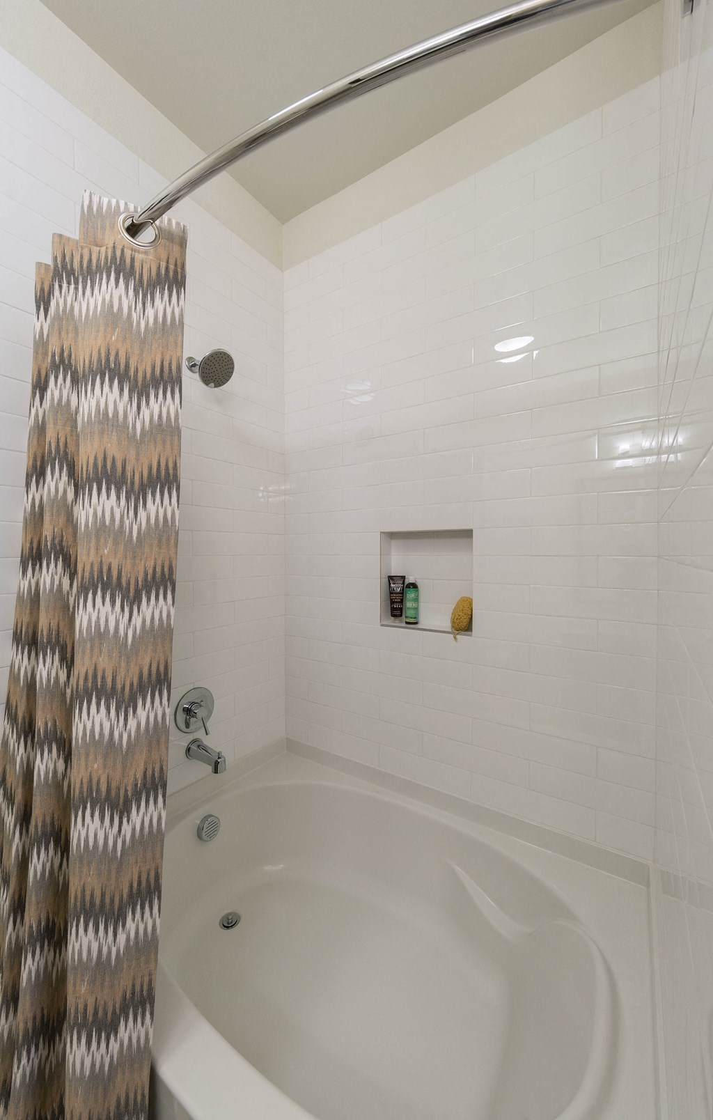 a bathroom with a white bathtub and a gray and white shower curtain