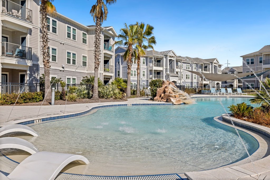 A swimming pool surrounded by palm trees and apartment buildings.