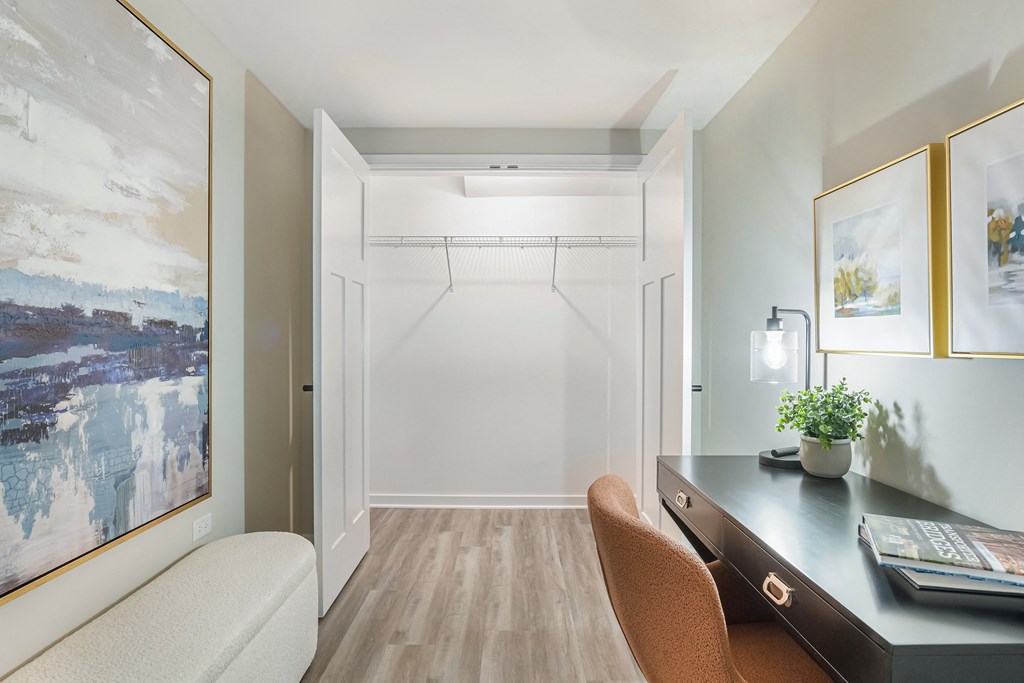 A room with a desk, chair, and a painting on the wall.