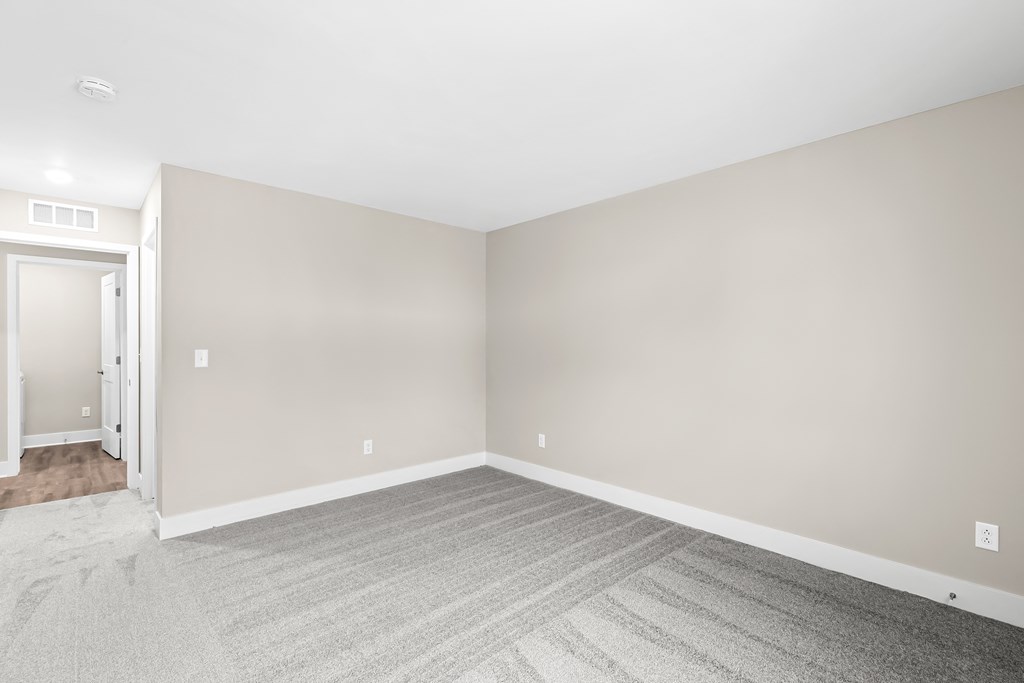 an empty room with white walls and gray carpet