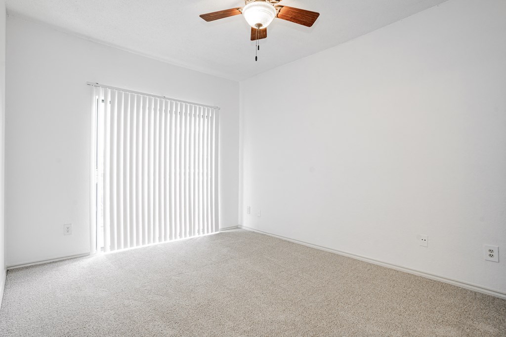 an empty living room with blinds and a ceiling fan