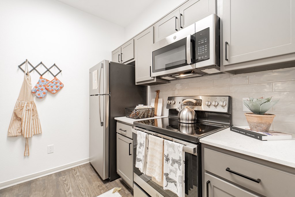 an apartment kitchen with stainless steel appliances and white cabinets
