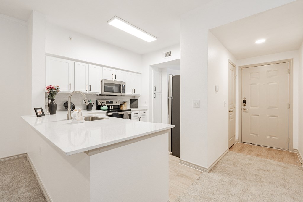 a white kitchen with a white counter top and a sink