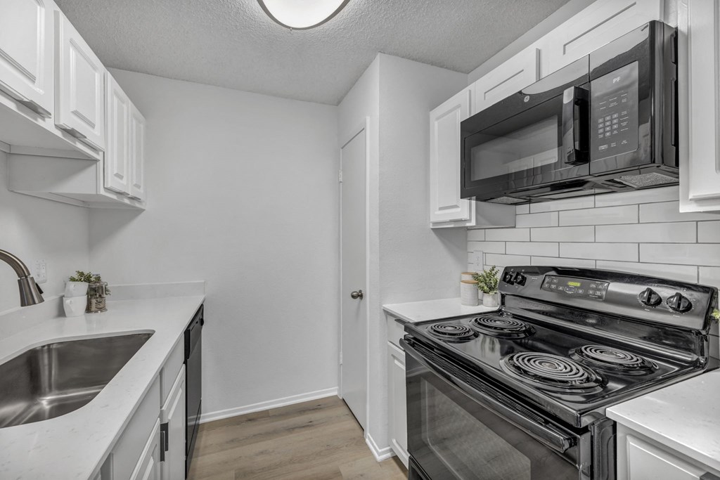A kitchen with a black microwave above the stove.