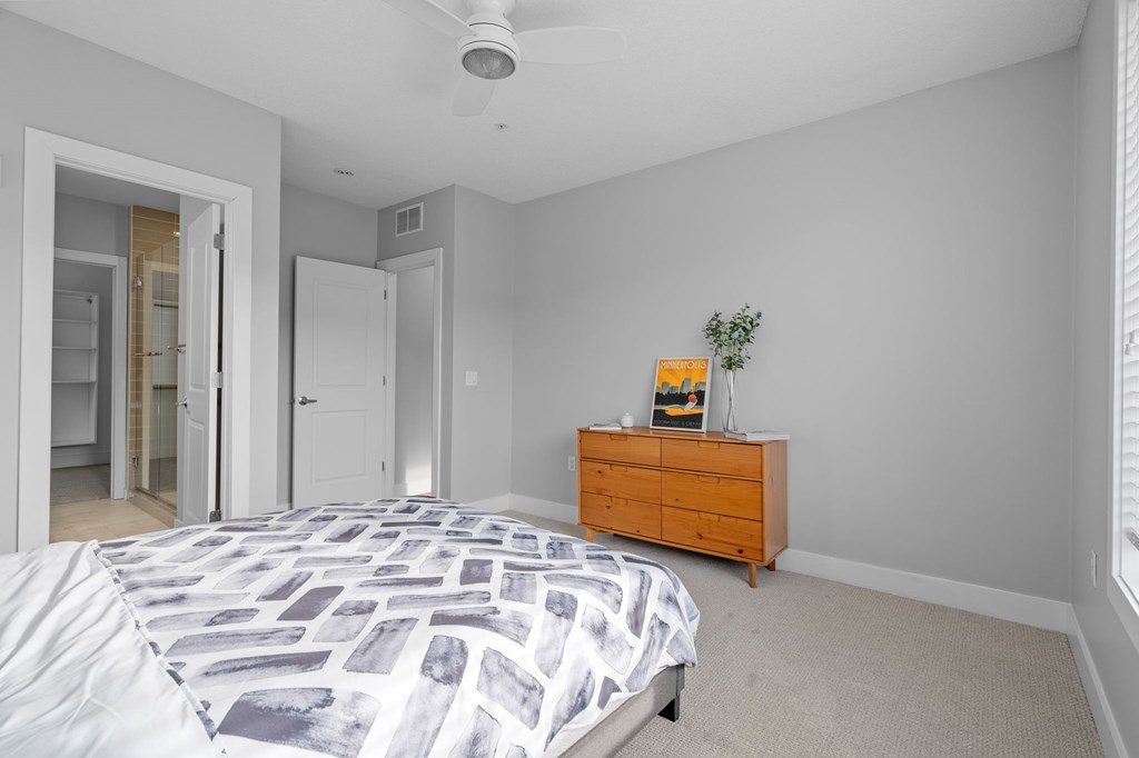 A bedroom with a bed, dresser, and ceiling fan.
