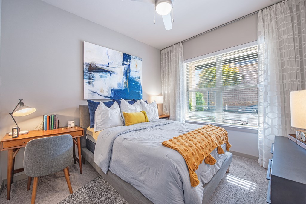 a bedroom with a bed and a desk and a window