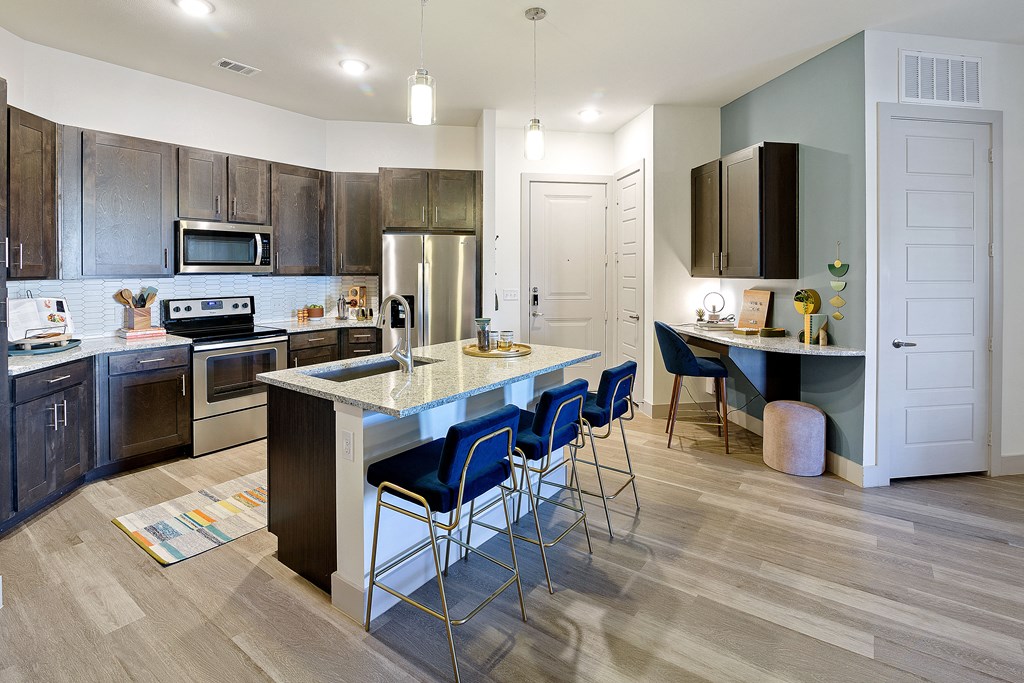 a kitchen with a large island with blue bar stools