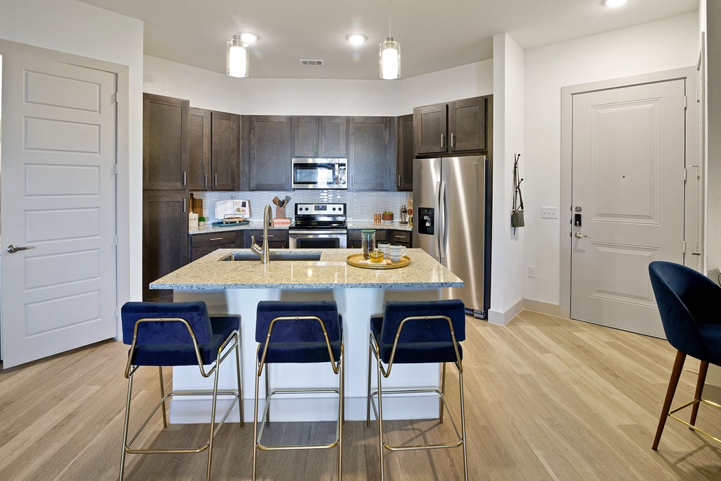 a kitchen with a marble counter top with blue chairs