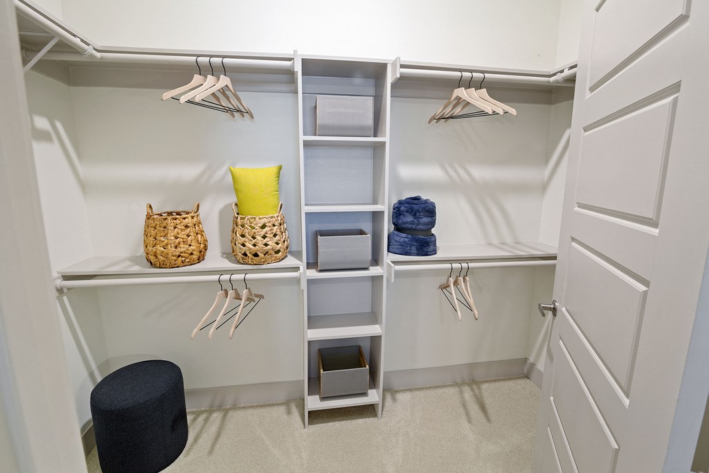 a walk in closet with white shelves and a closet organizer