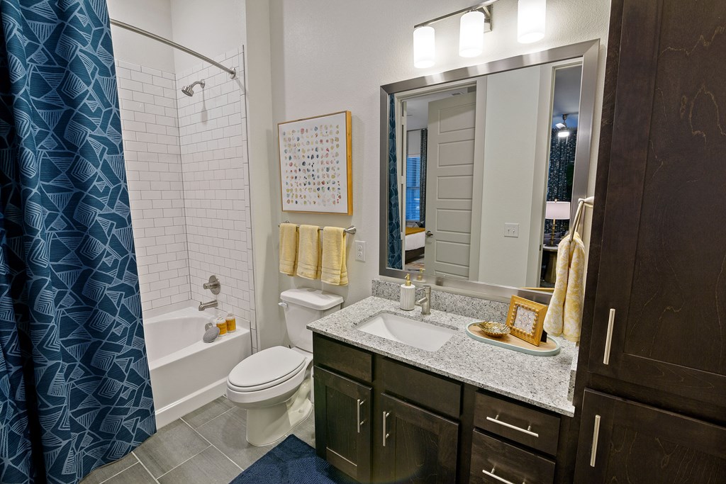 Bathroom with a tub shower and brown cabinets