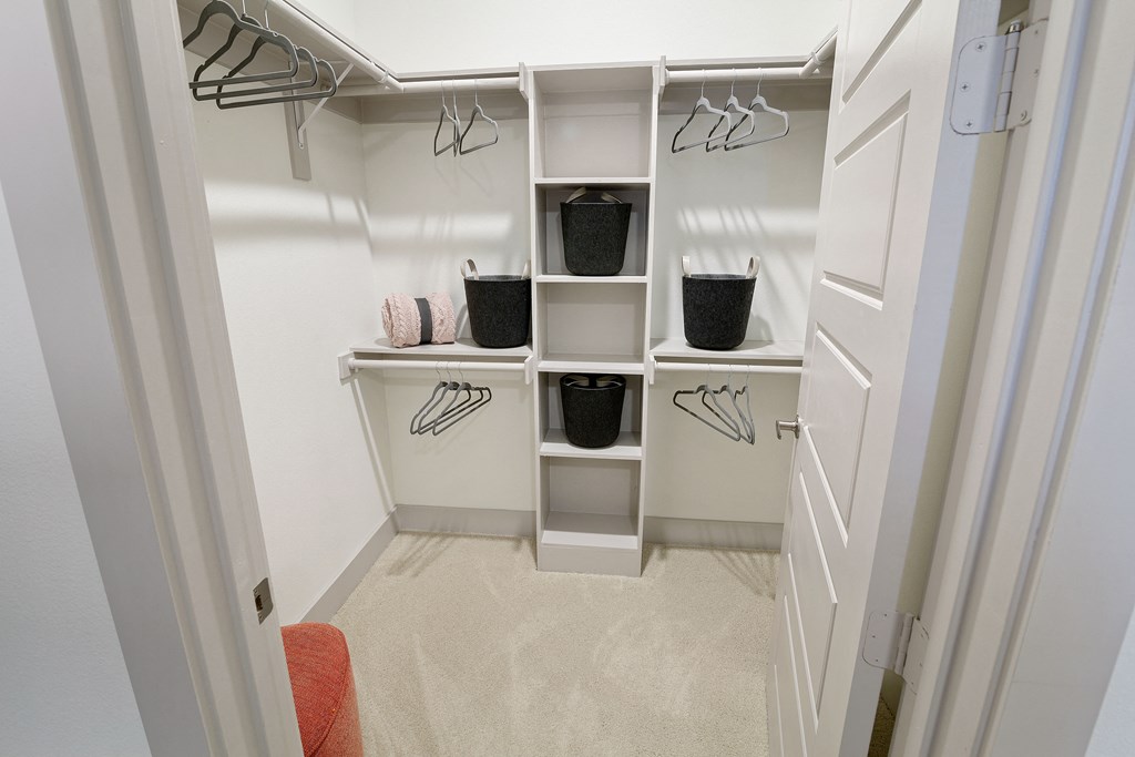 a walk in closet with white shelves  and built-ins