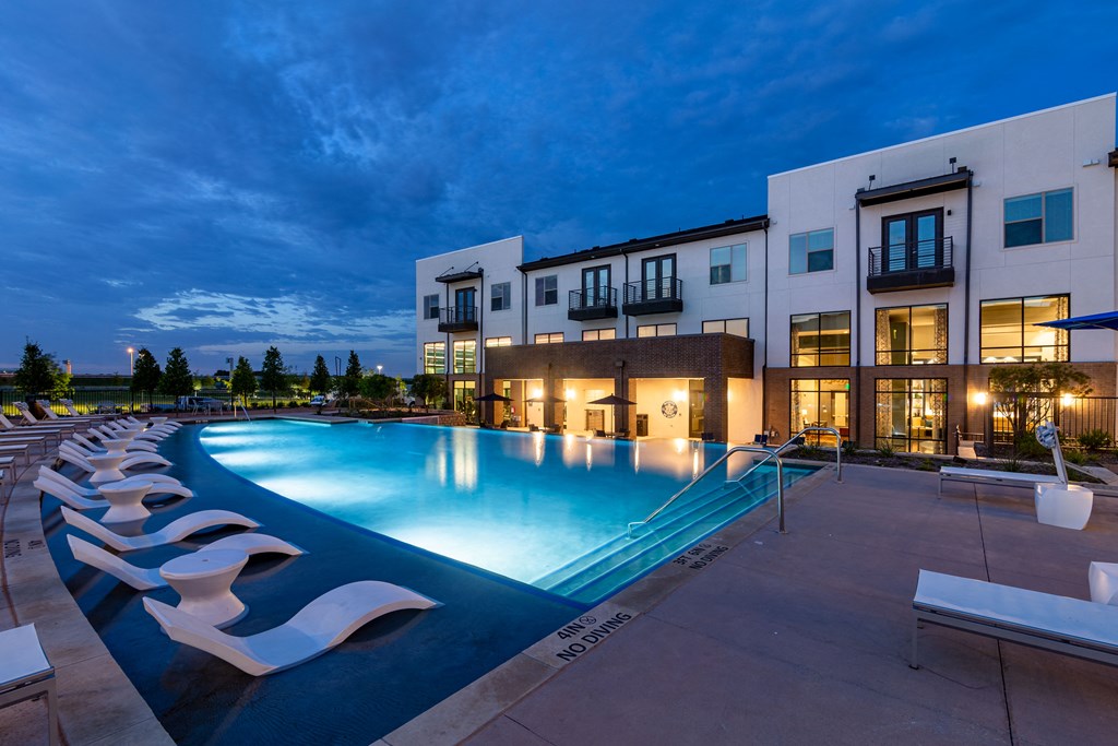 a swimming pool in front of a building at night