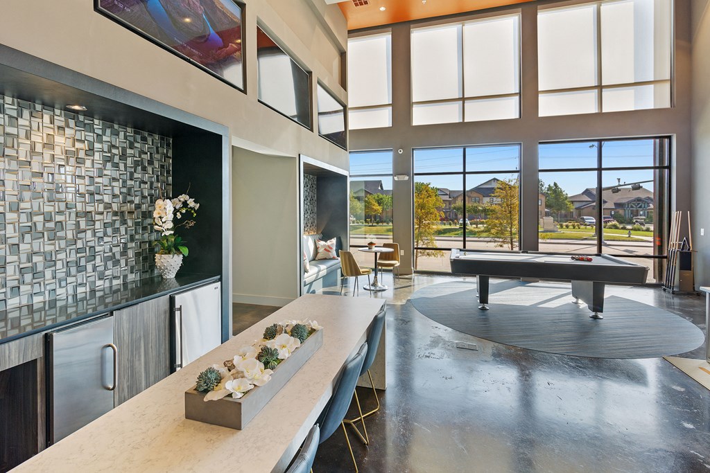 a living room with a ping pong table and a kitchen with a large window
