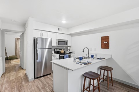 A kitchen with a refrigerator, microwave, and stove top oven.