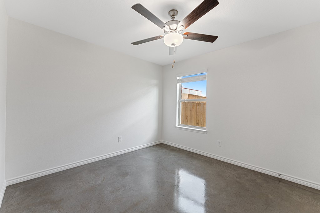 an empty room with a ceiling fan and a window