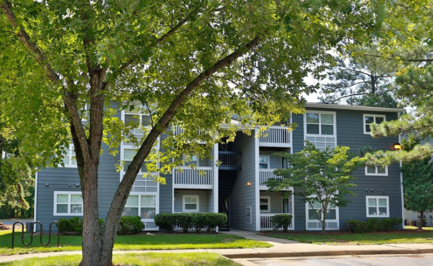 a gray apartment building with a tree in front of it