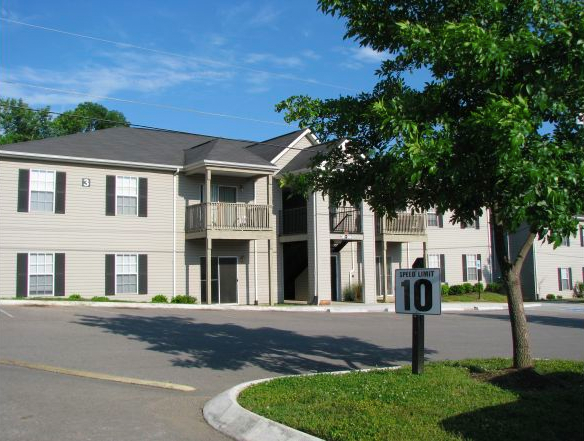 a street view of an apartment complex with a speed limit sign in the foreground