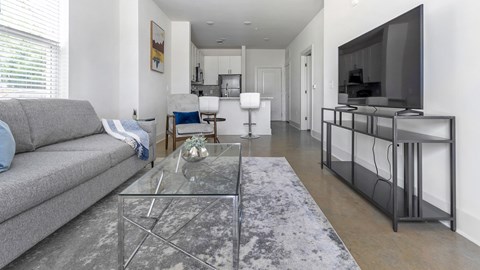 A modern living room with a grey sofa and a glass coffee table.