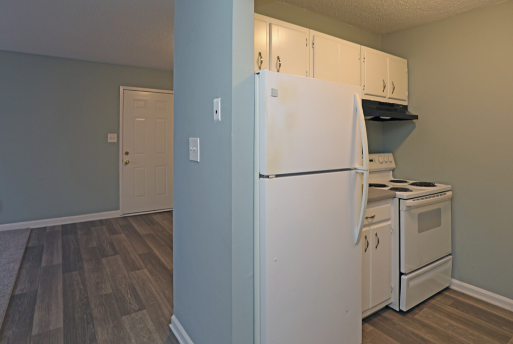 an empty kitchen with white appliances and a refrigerator