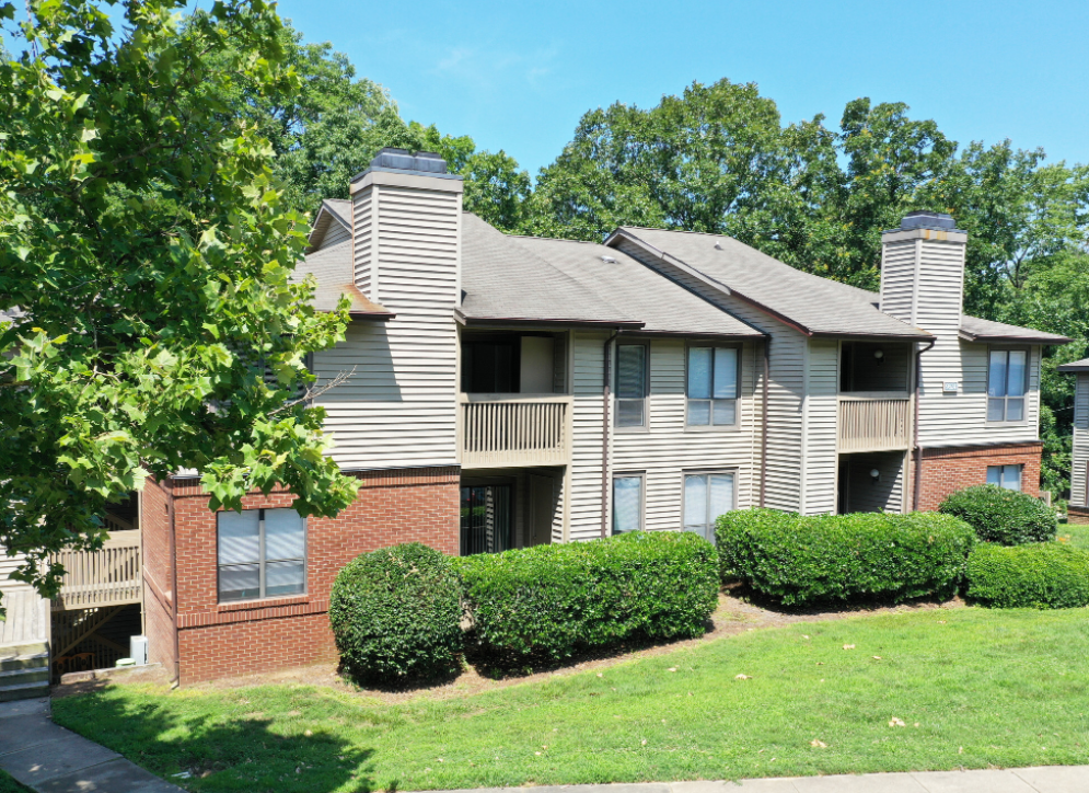 the outlook of an apartment building with a lawn and bushes
