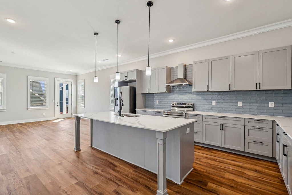 A modern kitchen with a large island and wooden floors.