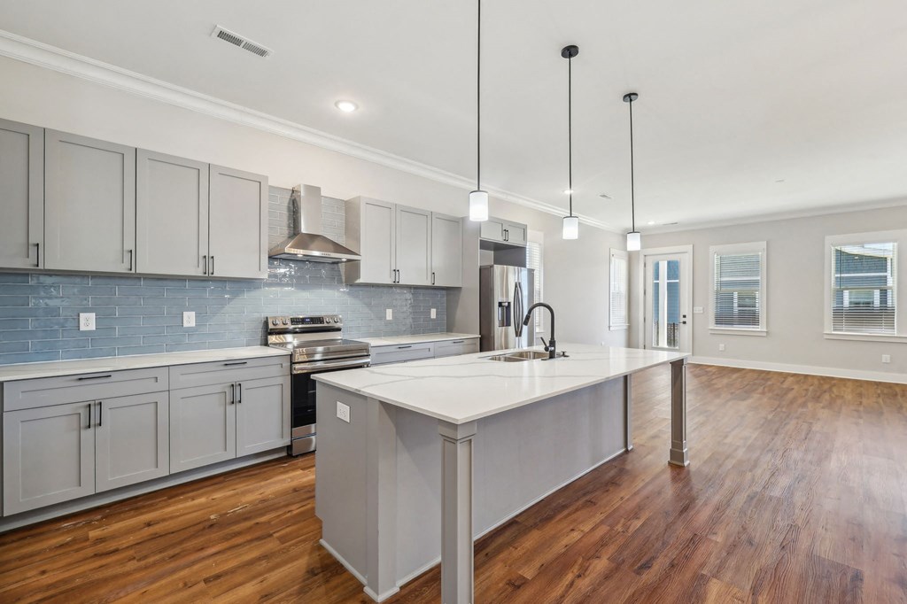 A modern kitchen with a large island and wooden floors.