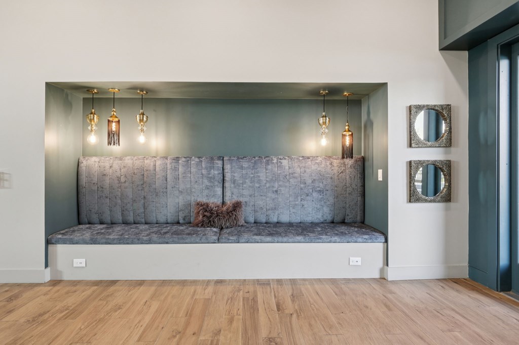 A grey couch with a pillow on it in a room with wooden floors.