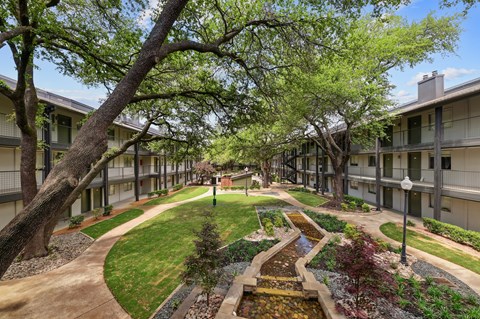 A courtyard with a water feature and trees.